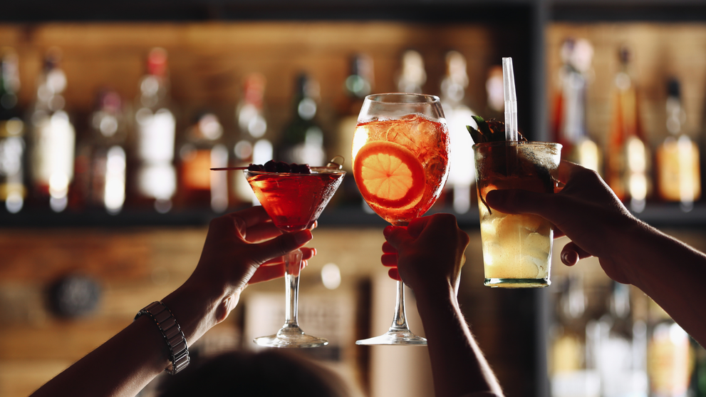 Friends toasting with beautifully garnished nonalcoholic cocktails during sober October. 