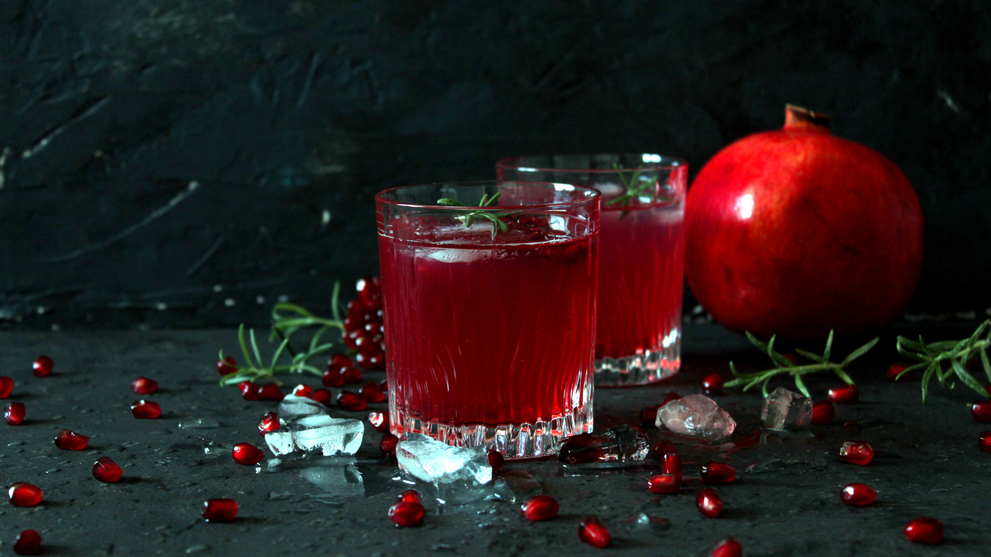 Pomegranate cocktails in glasses garnished with rosemary.