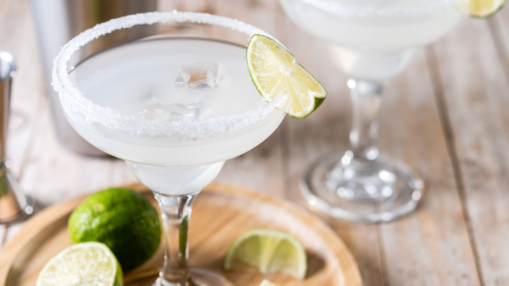 Two chilled margarita glasses with salted rims and fresh lime garnish.