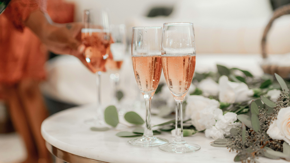 Two sparkling champagnes on a marble table styled with white flowers, perfect for a celebration.