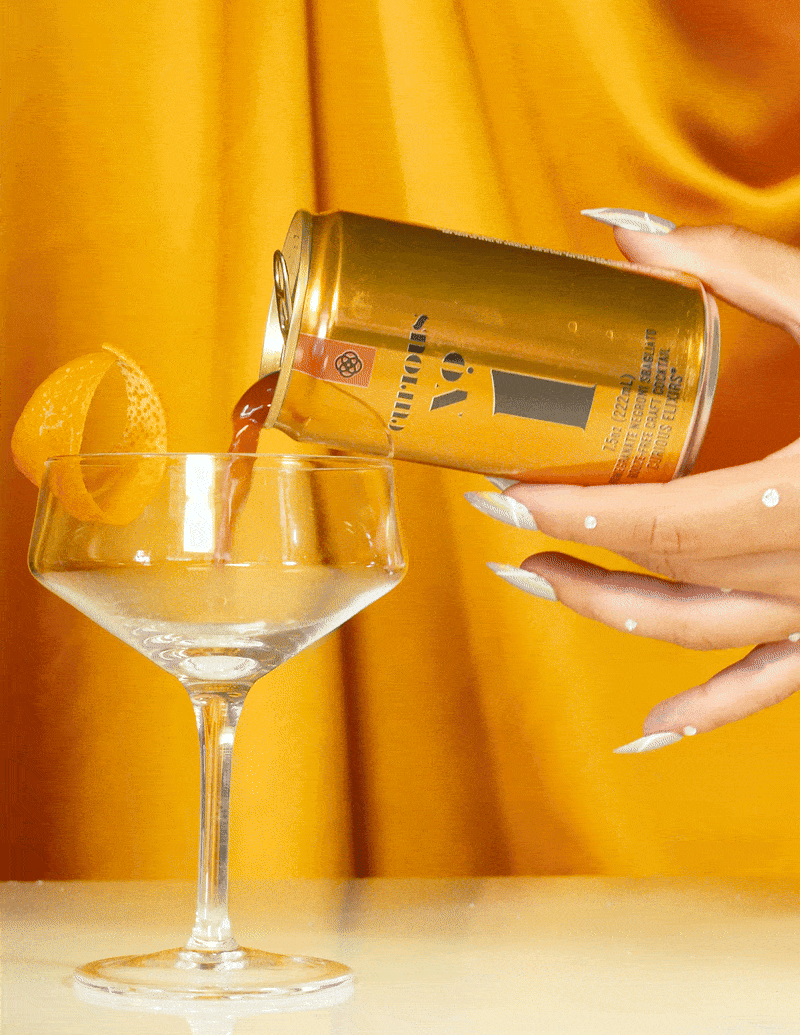 A hand with stylish nails pours a can of Curious No. 1 into a coupe.