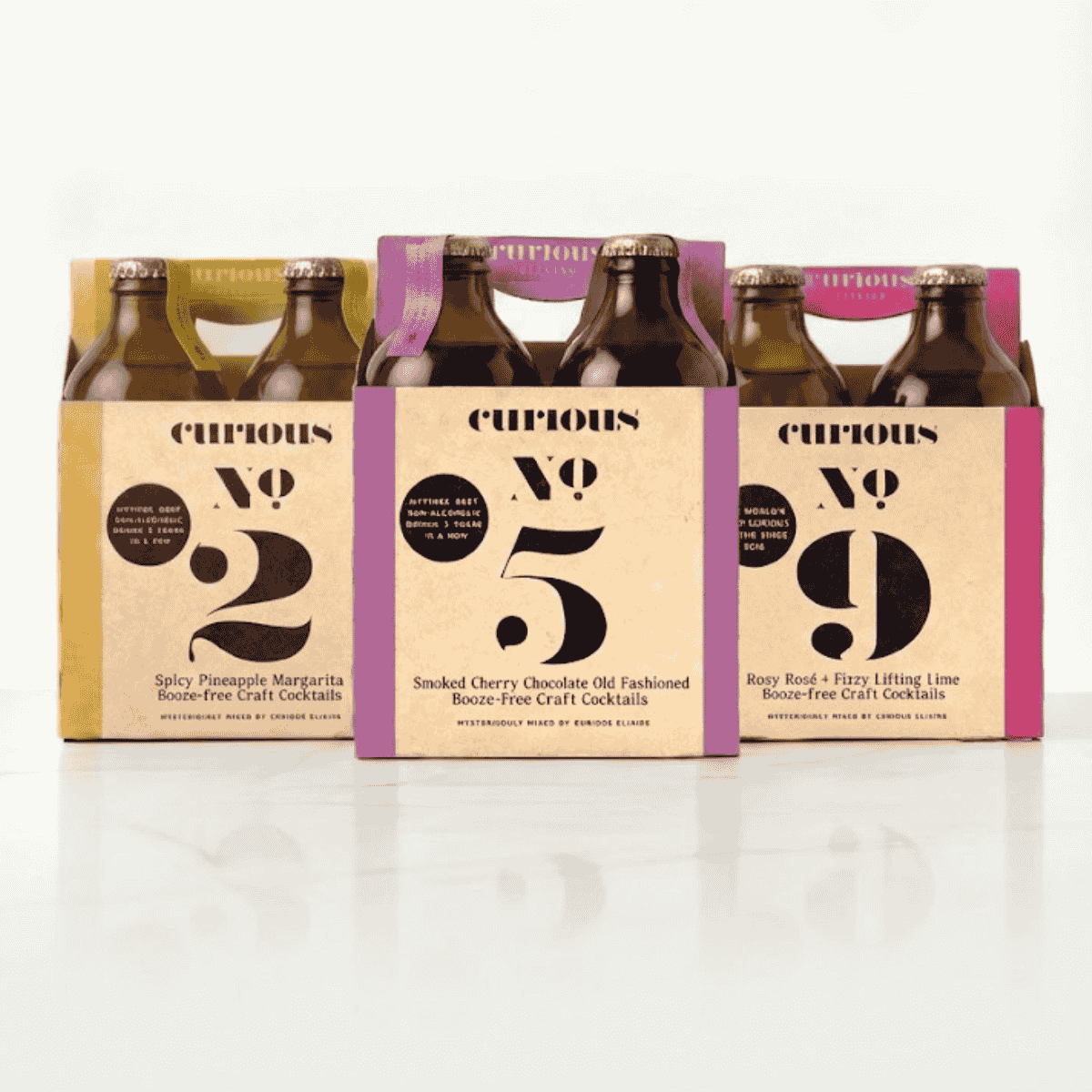 Three Curious Elixirs 4-packs displayed side by side, with No. 2 on the left, No. 5 in the center, and No. 9 on the right.